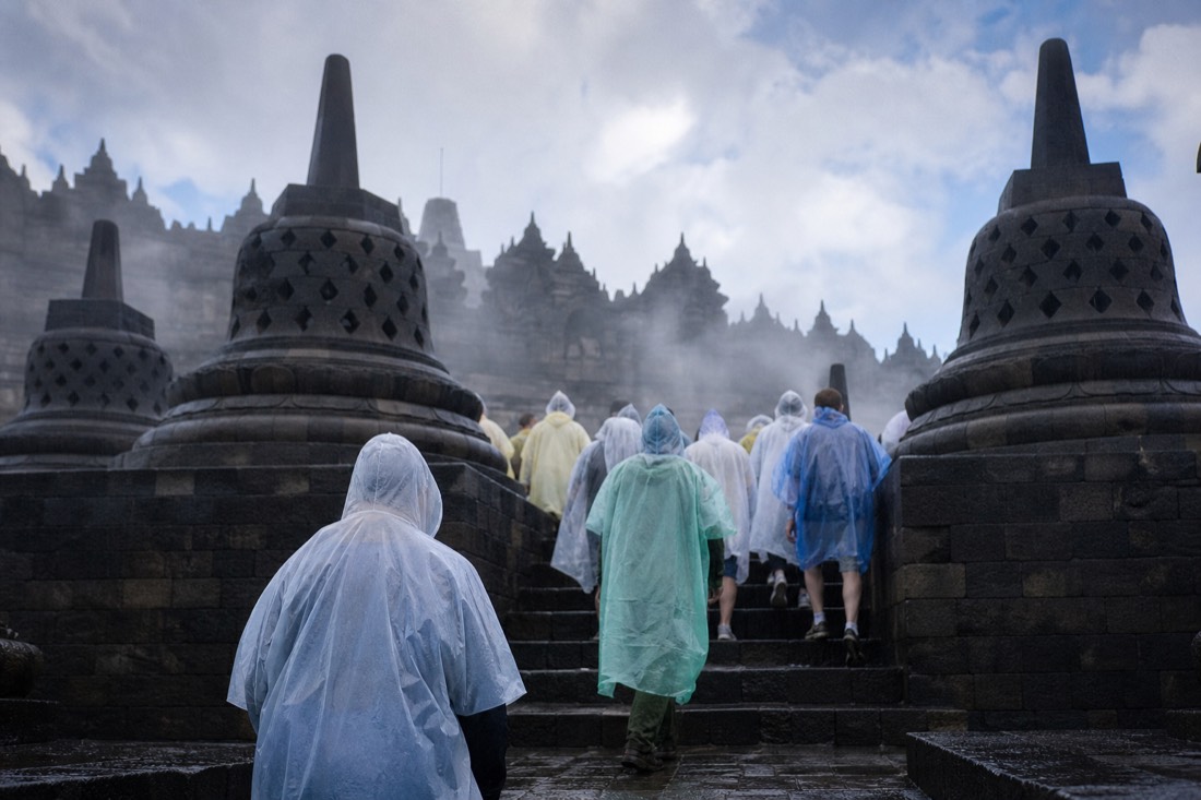 Climbing Borobudur's wet steps in rain ponchos