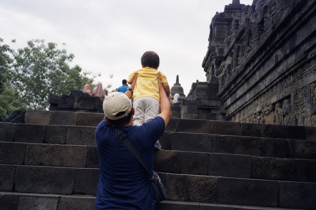 Helping a child up the tall steps of Borobudur