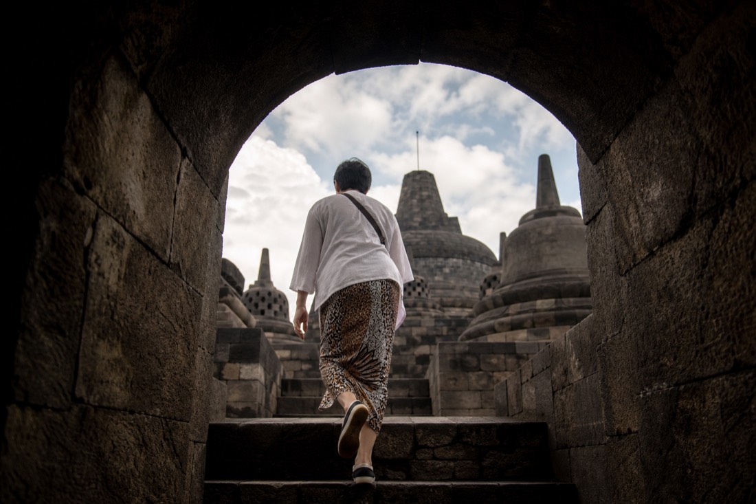 Ascending through a carved gateway arch at Borobudur